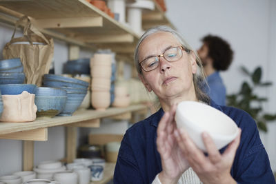 Mature woman examining bowl in art class