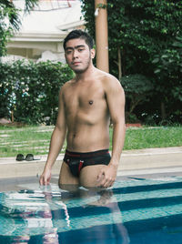 Portrait of shirtless man standing in pool