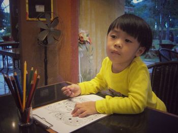 Portrait of cute boy sitting on table at home