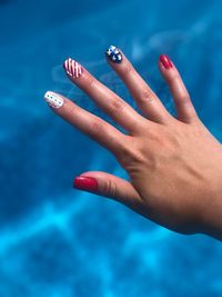 Close-up of woman hand against blue sky