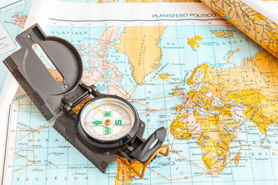 High angle view of navigational compass on world map