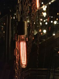 Close-up of illuminated light bulb hanging at night