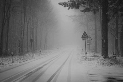 Road amidst trees in forest during winter