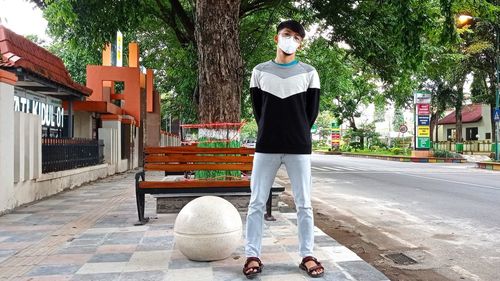 Full length portrait of young man standing on footpath