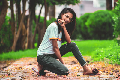 Portrait of woman smiling while kneeling at park