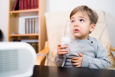 Boy looking up while holding respiratory mask at home
