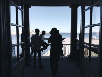 People standing in building by railing against sea