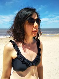 Young woman wearing sunglasses on beach against sky