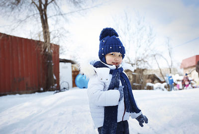 Portrait of cute girl wearing warm clothing while standing on snowy field