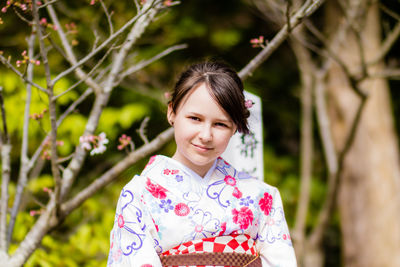 Portrait of smiling woman in kimono against trees