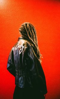 Rear view of woman standing against red wall