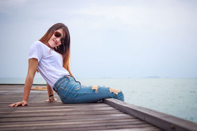 Full length of woman sitting on shore against sky