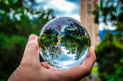 Cropped image of hand holding crystal ball with reflection