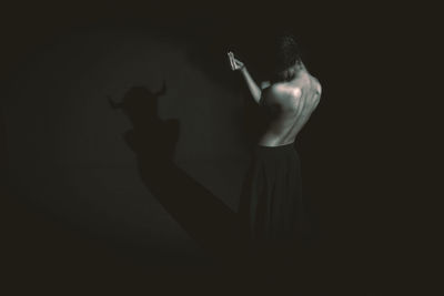 Silhouette woman with arms raised against black background