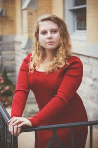 Portrait of young woman standing against railing