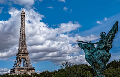 Low angle view of statue of tower against cloudy sky