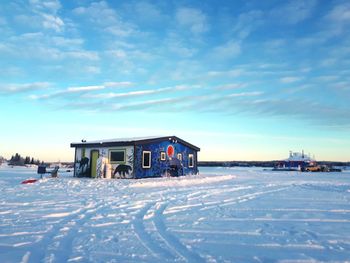 House on snow covered houses by building against sky