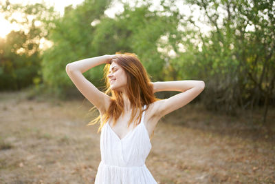 Woman with arms raised standing on tree