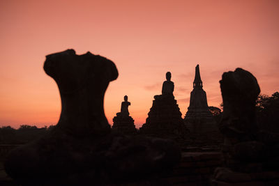 Low angle view of silhouette buddha statues against sky during sunset