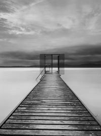 Wooden jetty on pier over lake against sky