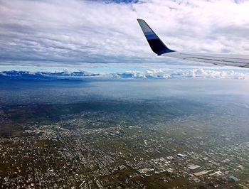 Airplane flying over landscape against cloudy sky