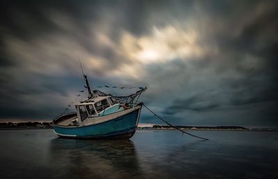 Boats in sea against cloudy sky