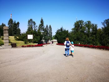 Rear view of boy with mother walking on road 