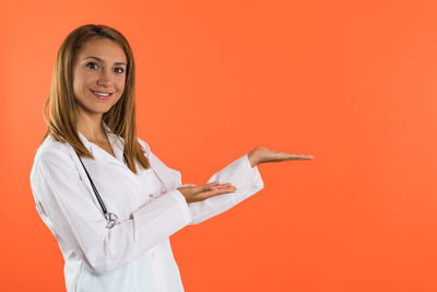 Portrait of young woman standing against yellow background