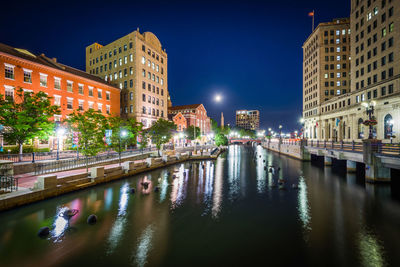 Canal amidst illuminated buildings in city at night