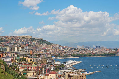 Cityscape at sea shore against sky