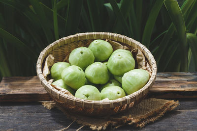 Close-up of green fruits in basket on wooden table