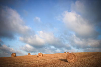 Hay bales on field against sky