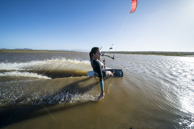 Happy female kiteboarder skims the water with her hand in mexico
