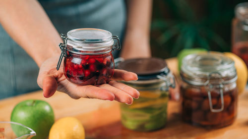 Woman holding jars with fermented fruits.