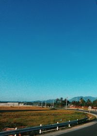 Road by landscape against clear blue sky