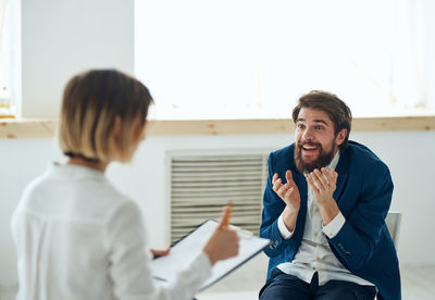 Side view of young woman using mobile phone while standing in office