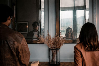 Rear view of people sitting on table by window