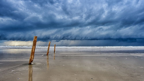 Wooden posts on beach against sky