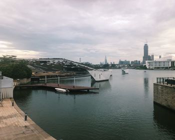 Bridge over river by buildings in city against sky