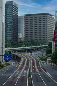 Road by buildings in city against sky aoyama street 