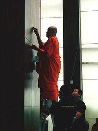 Rear view of man standing by window