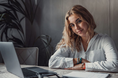 Young woman using laptop while sitting on sofa at home