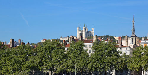Panoramic view of trees and buildings against blue sky