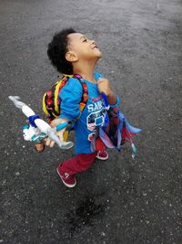 High angle view of smiling boy holding toy while standing on road