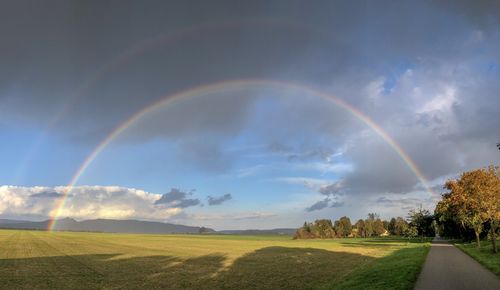 Scenic view of rainbow over field against sky