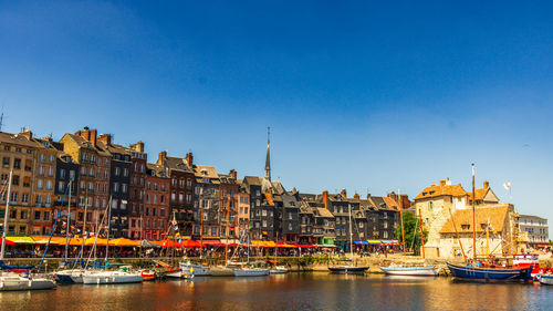 Boats in sea against clear blue sky