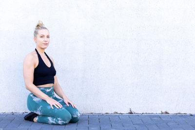 Portrait of young woman standing against wall