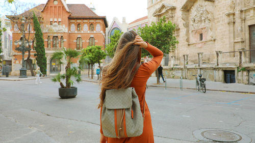 Rear view of woman standing on road in city