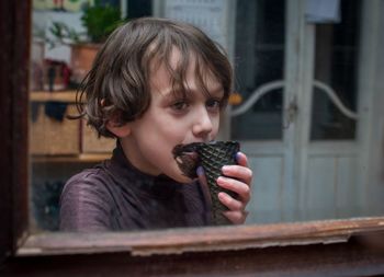 Portrait of cute boy holding ice cream window