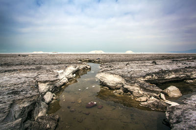 Scenic view of rocks on shore against sky